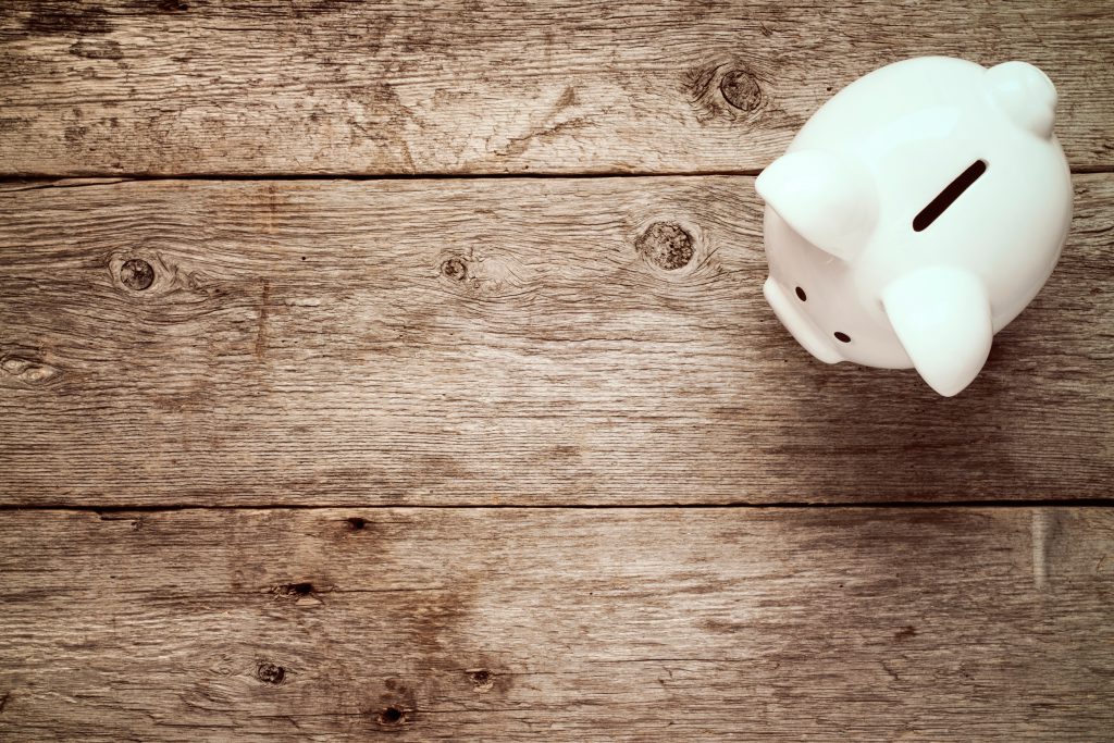 Piggy bank on the old wooden background, top view